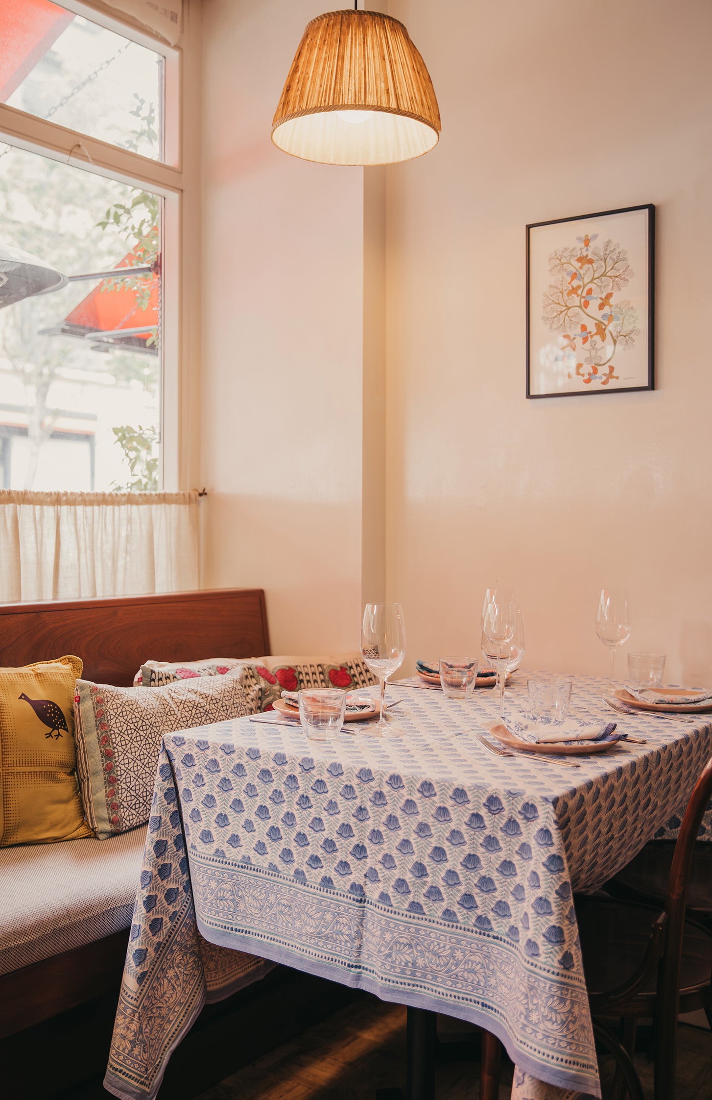 Jikoni dining room with a table set for four, patterned tablecloth, and decorative pillows.