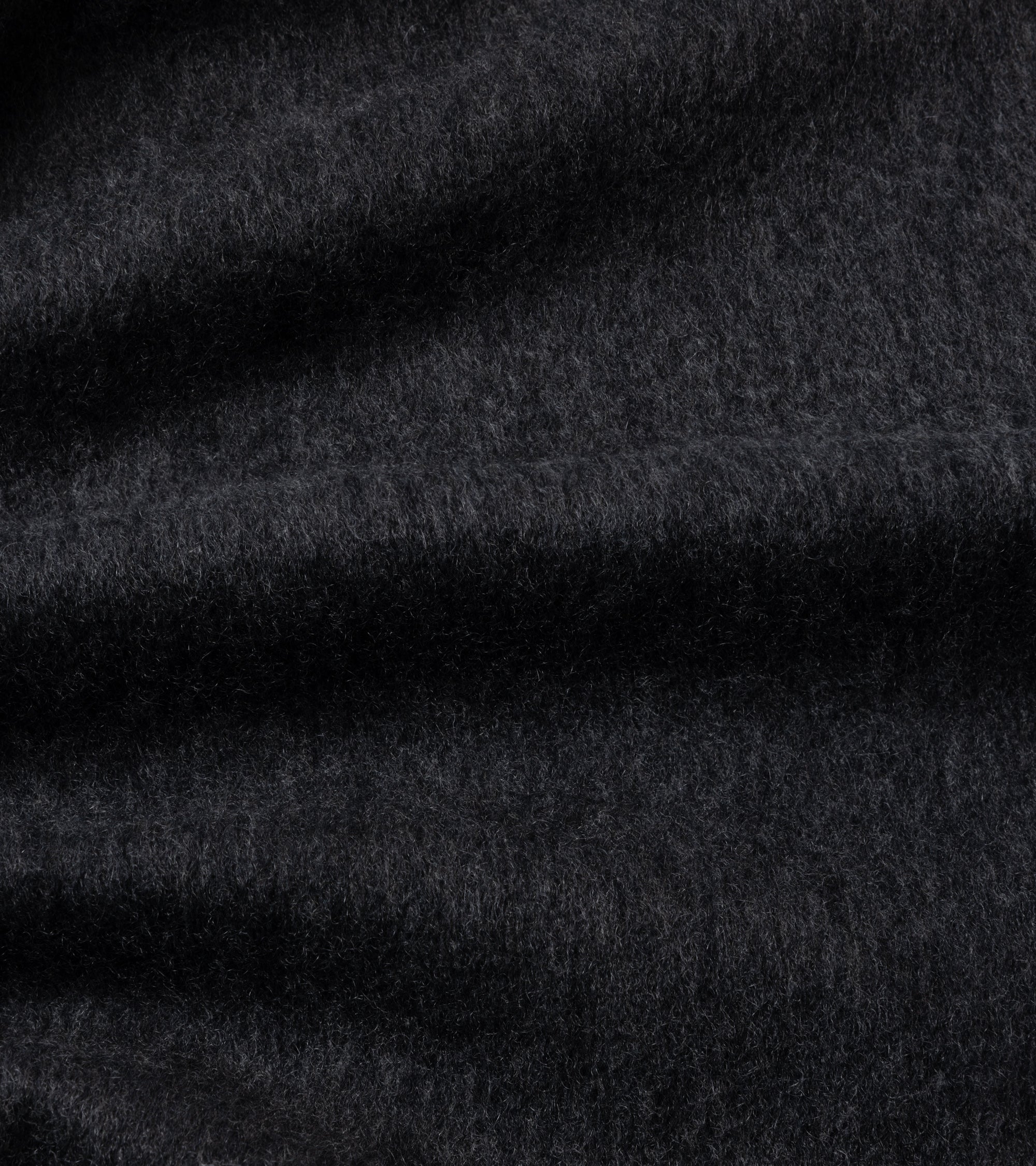 A close-up of dark charcoal gray textured fabric with soft folds and a fine, slightly fuzzy surface.
