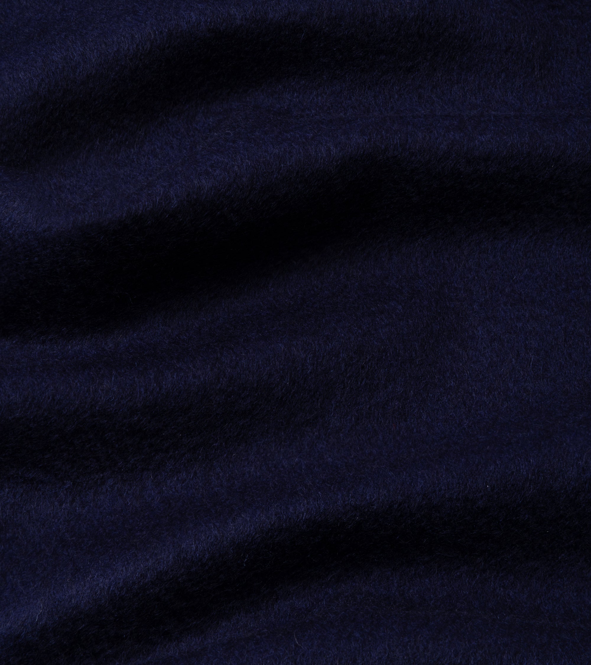 A close-up of dark navy blue plush fabric with soft folds and a textured, fuzzy surface.