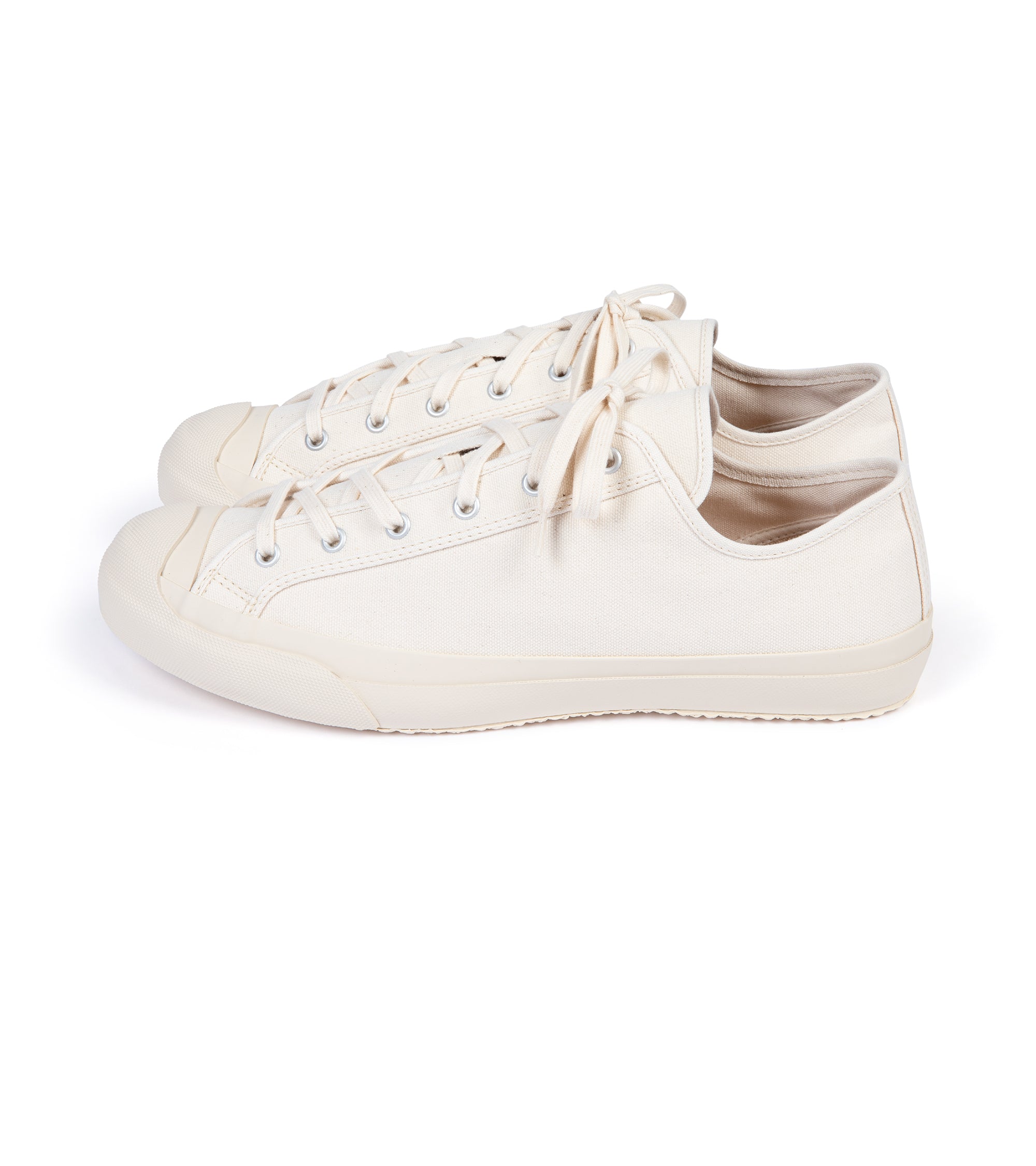 A pair of beige canvas sneakers with lace-up closure, displayed against a white background.