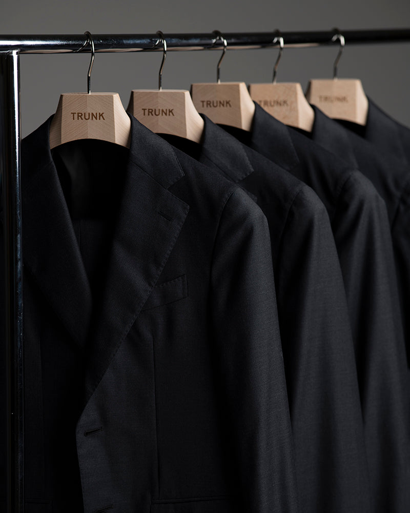 Black jackets on hangers with 'TRUNK' labels against a dark background
