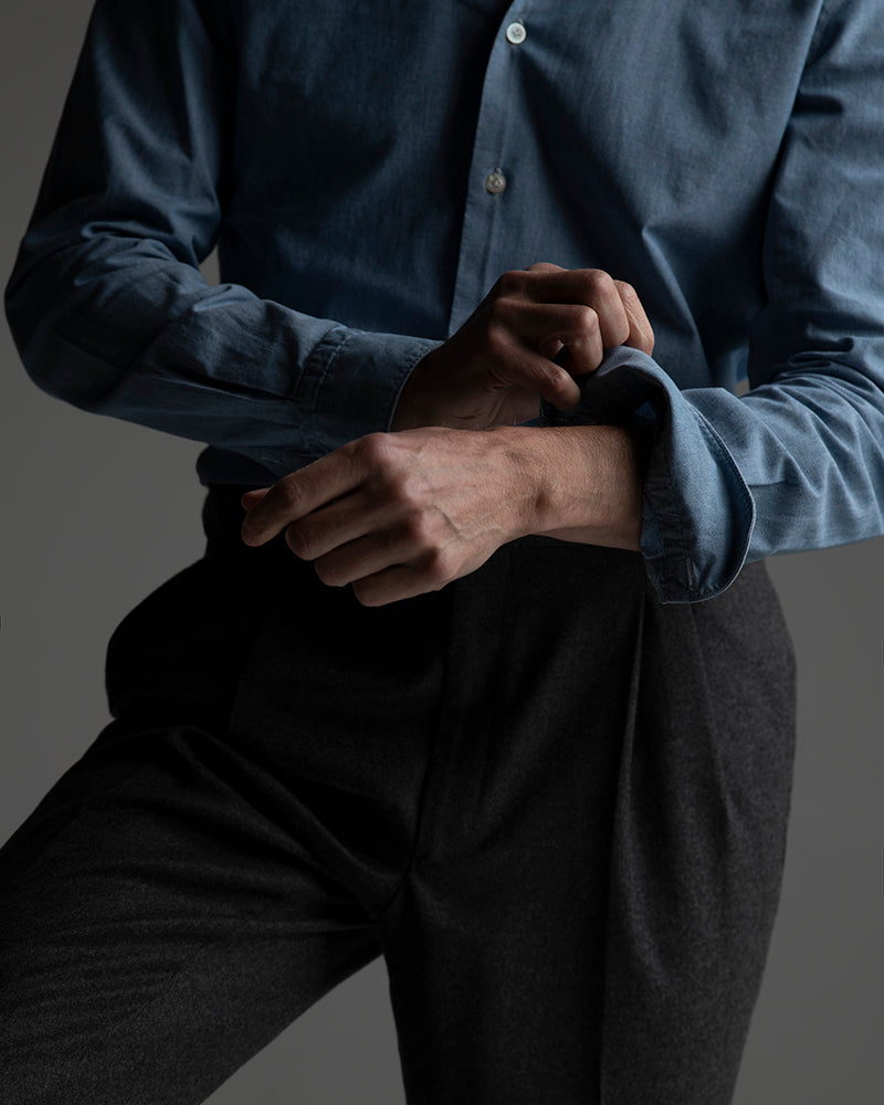 Person wearing a dark blue shirt and black pants against a gray background